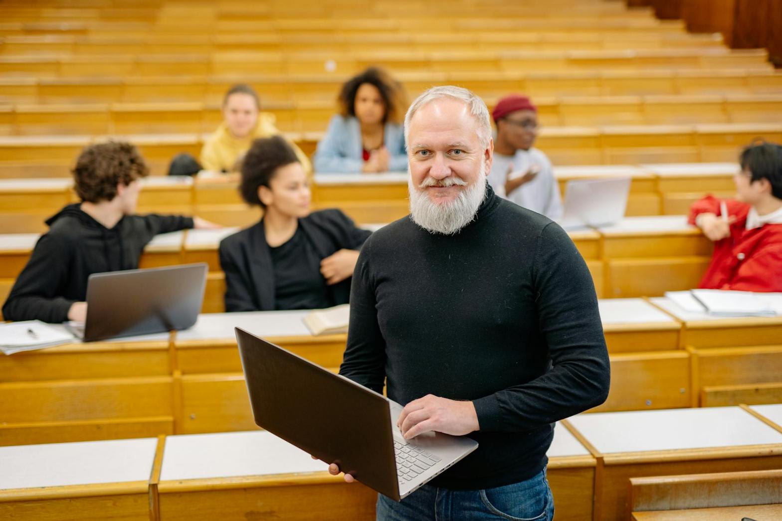 professor holding laptop in lecture hall with students present   dr krishna athal