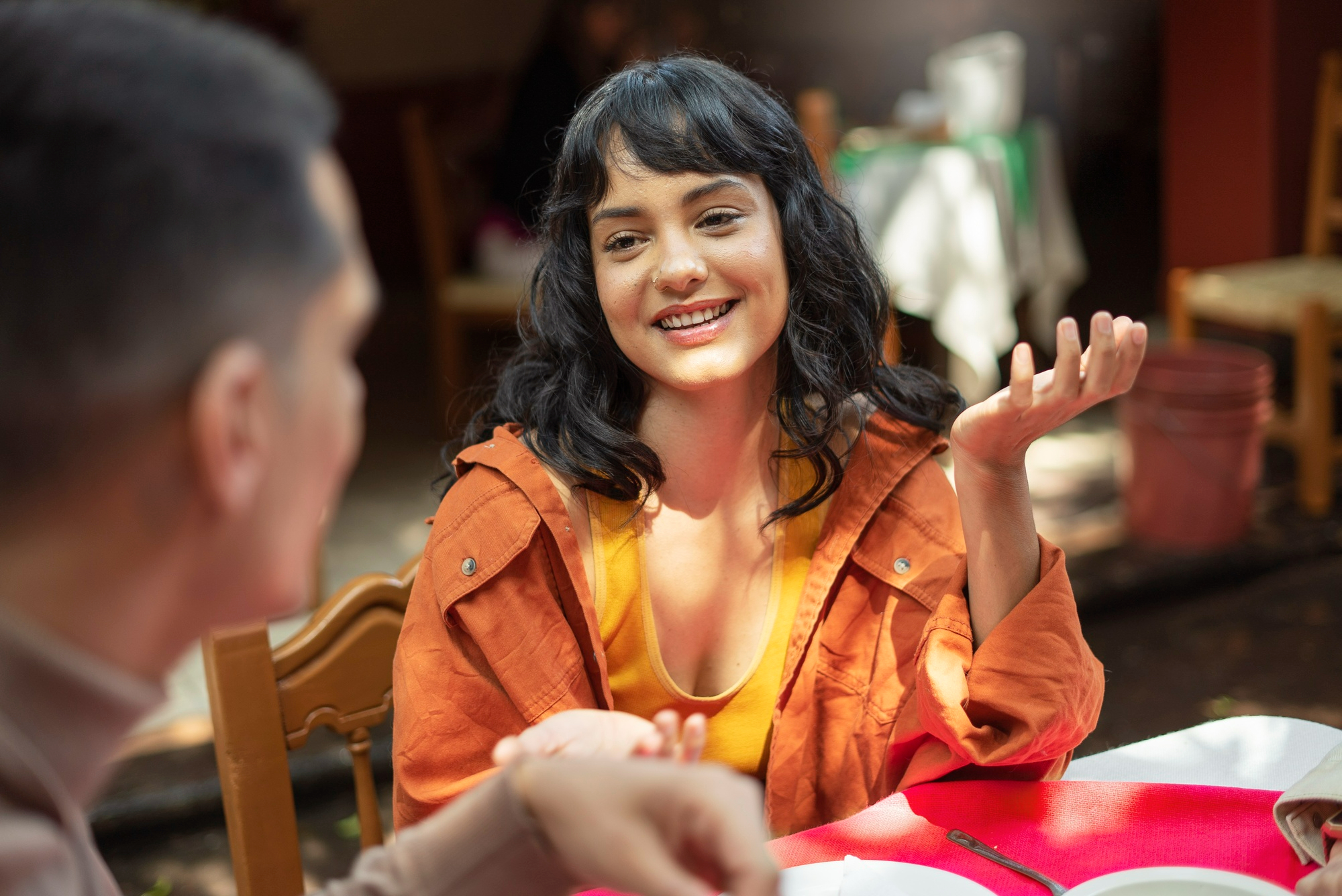 a coaching conversation that shifts perspective dr krishna athal smiling woman chatting at an outdoor café gesturing mid conversation in warm sunlight dr krishna athal